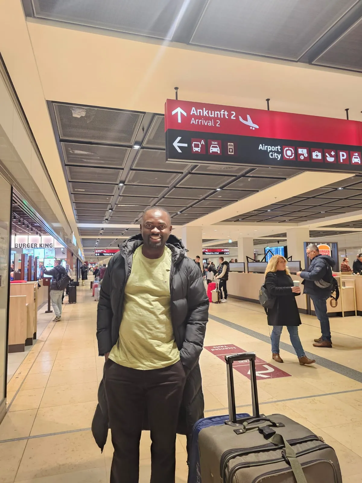 Leo Sokeng mit Koffer in einem Flughafen-Terminal