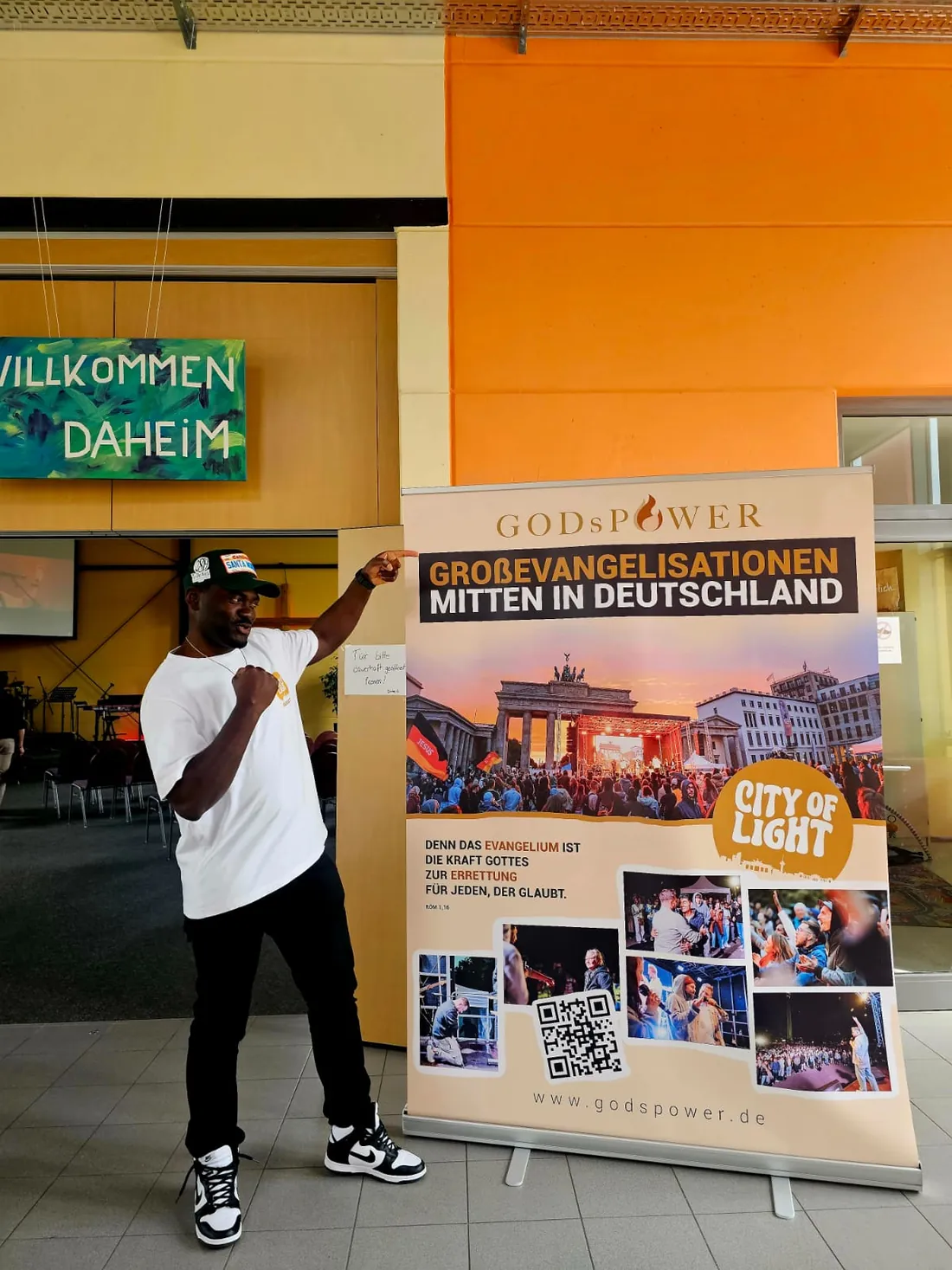 Leo Sokeng vor einem Plakat für Großevangelisationen in Deutschland