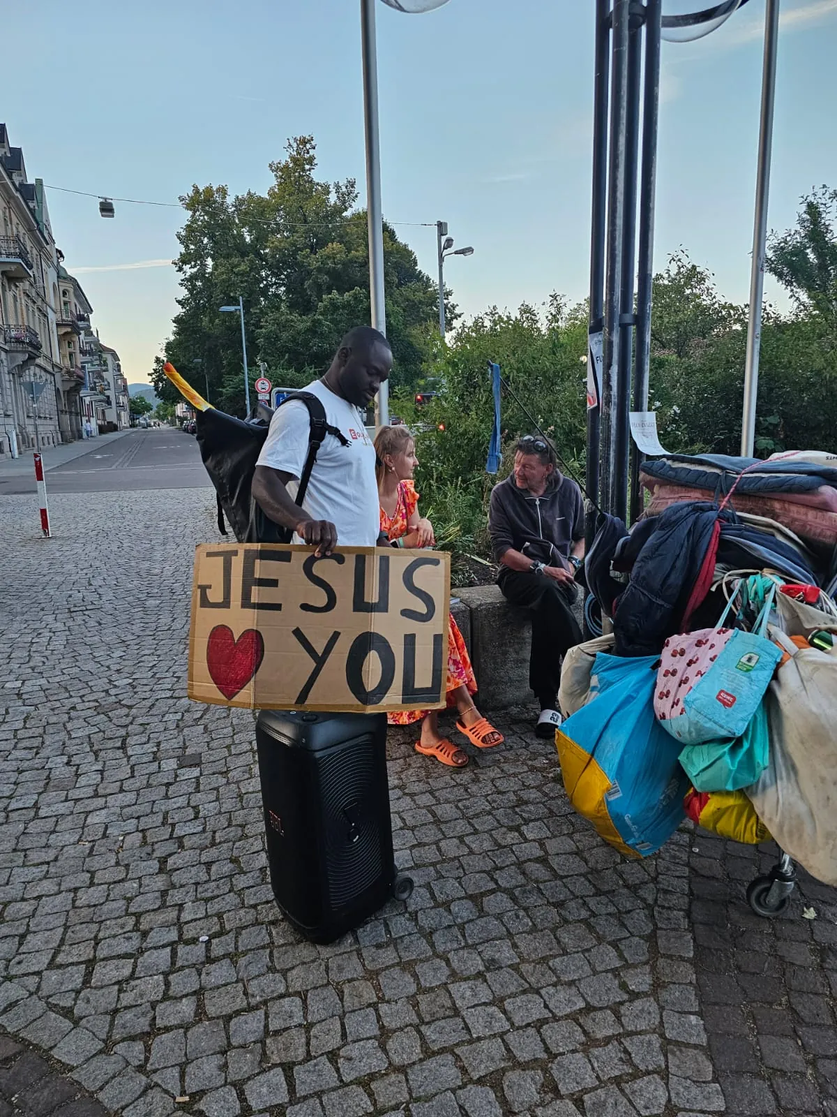 Begegnung mit Menschen auf der Straße, Schild „Jesus loves you“